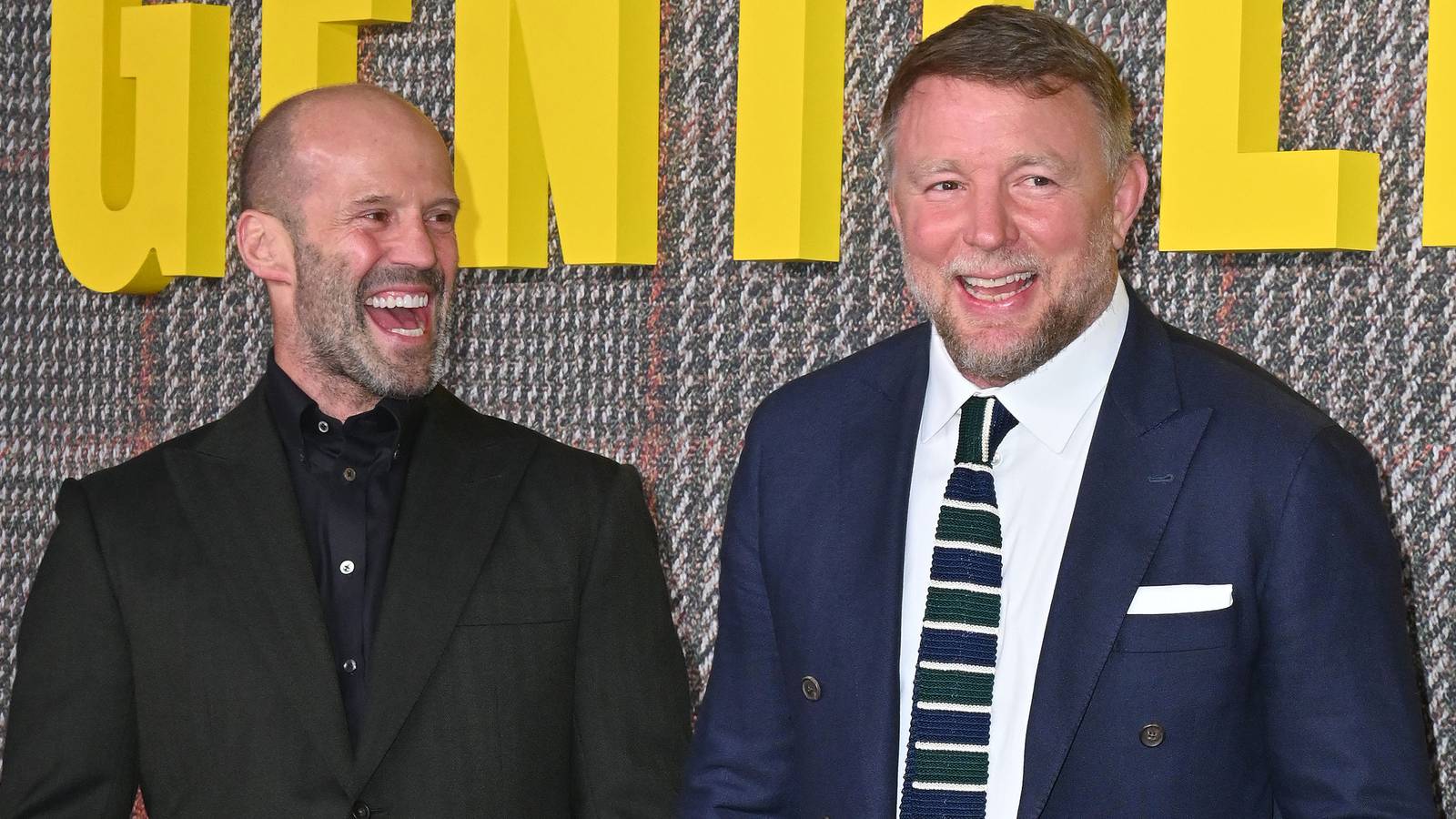 Jason Statham and Guy Ritchie smile at one another on the red carpet