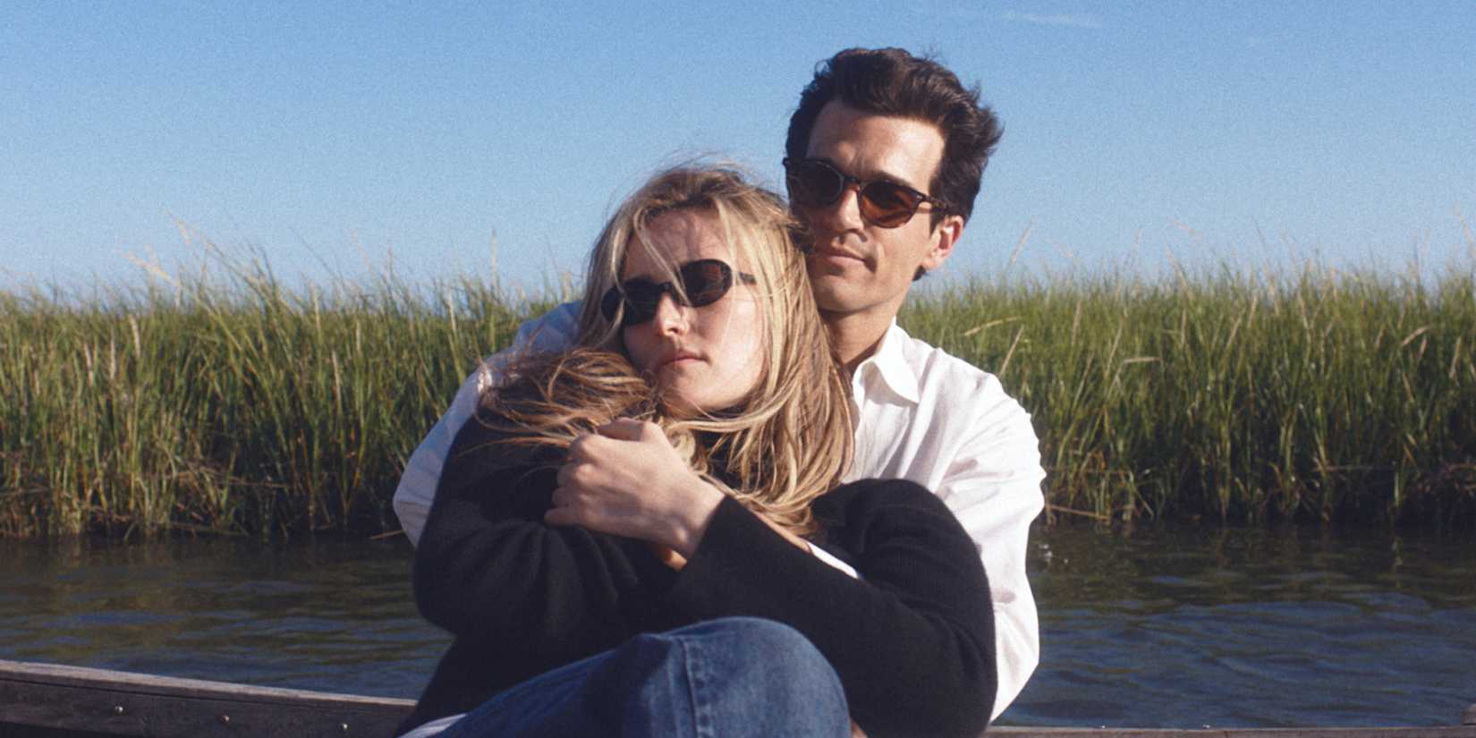 JFK Jr. holding Carolyn Bessette in front of tall grass