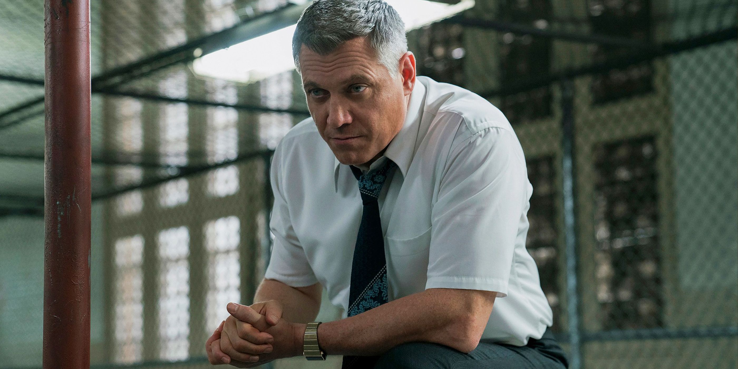 Bill leaning forward in front of a chain link barrier