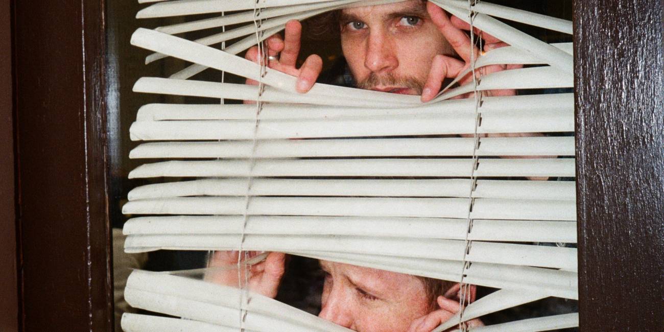 Two men looking out of blinds in 'Neighbors'