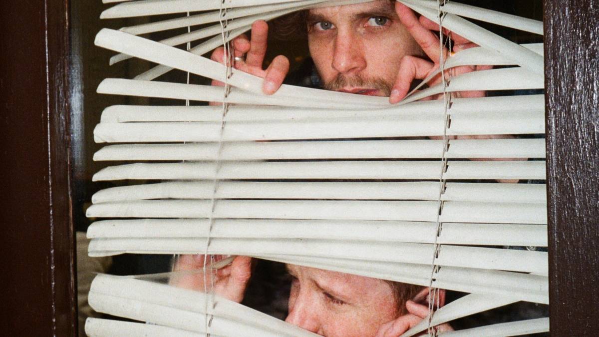 Two men looking out of blinds in 'Neighbors'