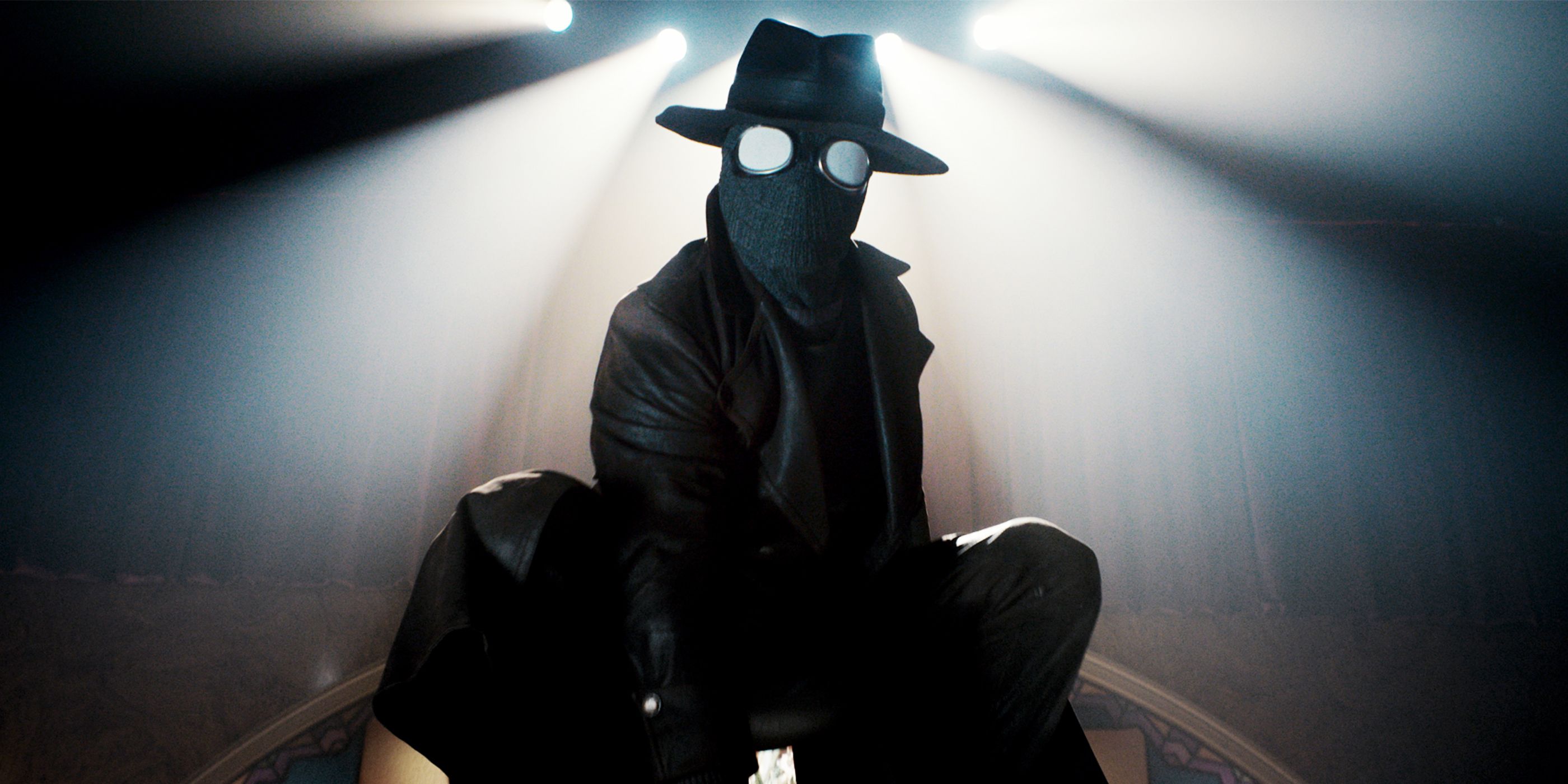 Nicolas Cage crouched on a desk in-costume in Spider-Noir