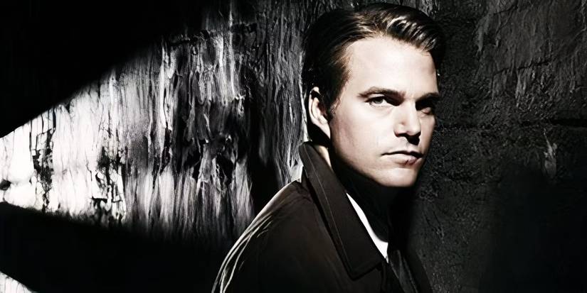 A man looking at the camera in a dark room in The Company miniseries