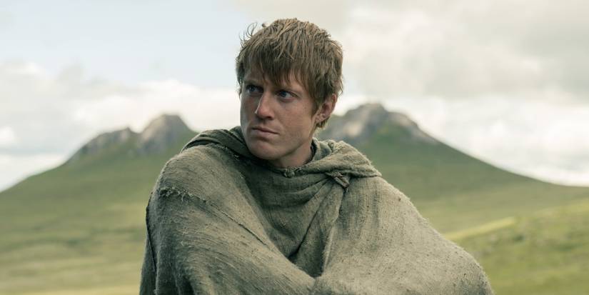 Peter Claffey as Dunk sitting while wearing a poncho and looking right in A Knight of the Seven Kingdoms