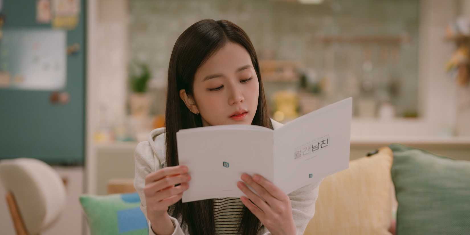 Jisoo browsing a booklet while sitting in her pastel-decorated home in Boyfriend on Demand