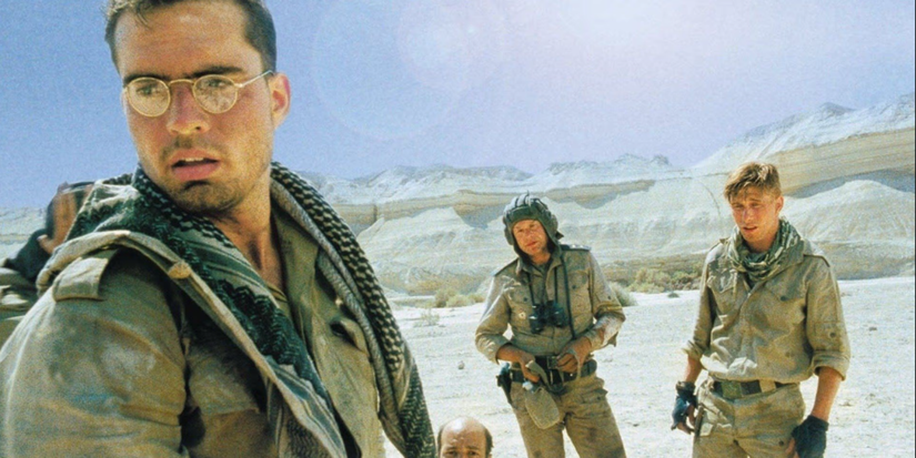 Group of soldiers stand in a harsh desert landscape, looking tense and alert in The Beast