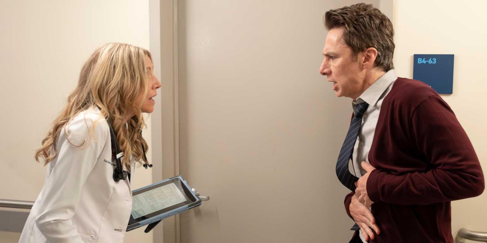 Zach Braff as J.D. holding his stomach in the hall across from Sarah Chalke as Elliot in the Scrubs revival