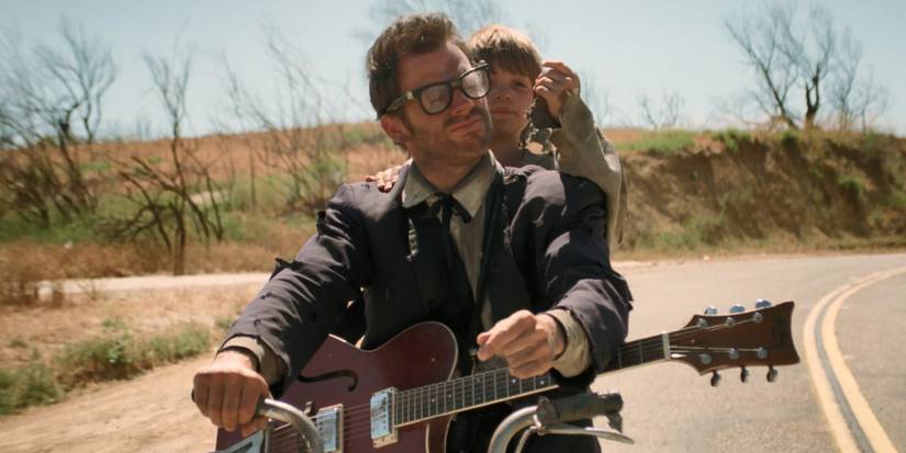 A man holding a guitar riding a bike in Six-String Samurai (1998)