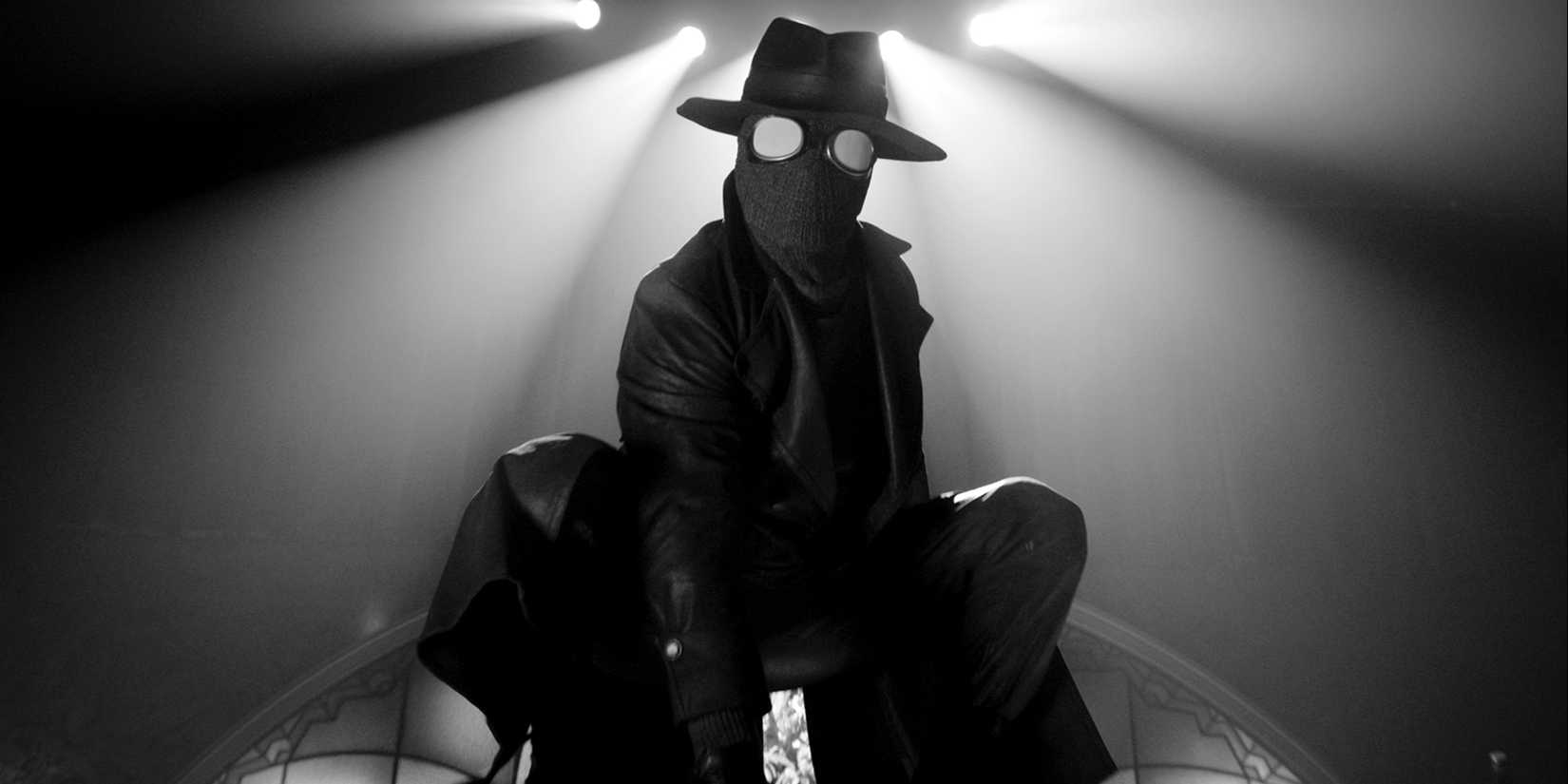 Nicolas Cage pointing a gun down at someone in Spider-Noir