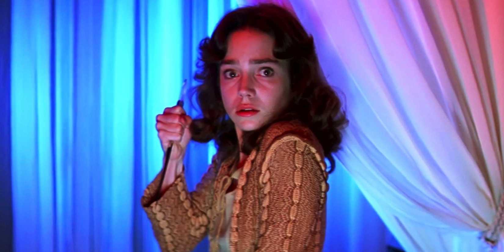 Jessica Harper holding a knife and looking at the camera with a scared expression in Suspiria