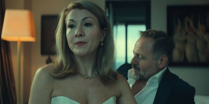 Genija Rykova sits on a bed with a man behind her in Unfamiliar.