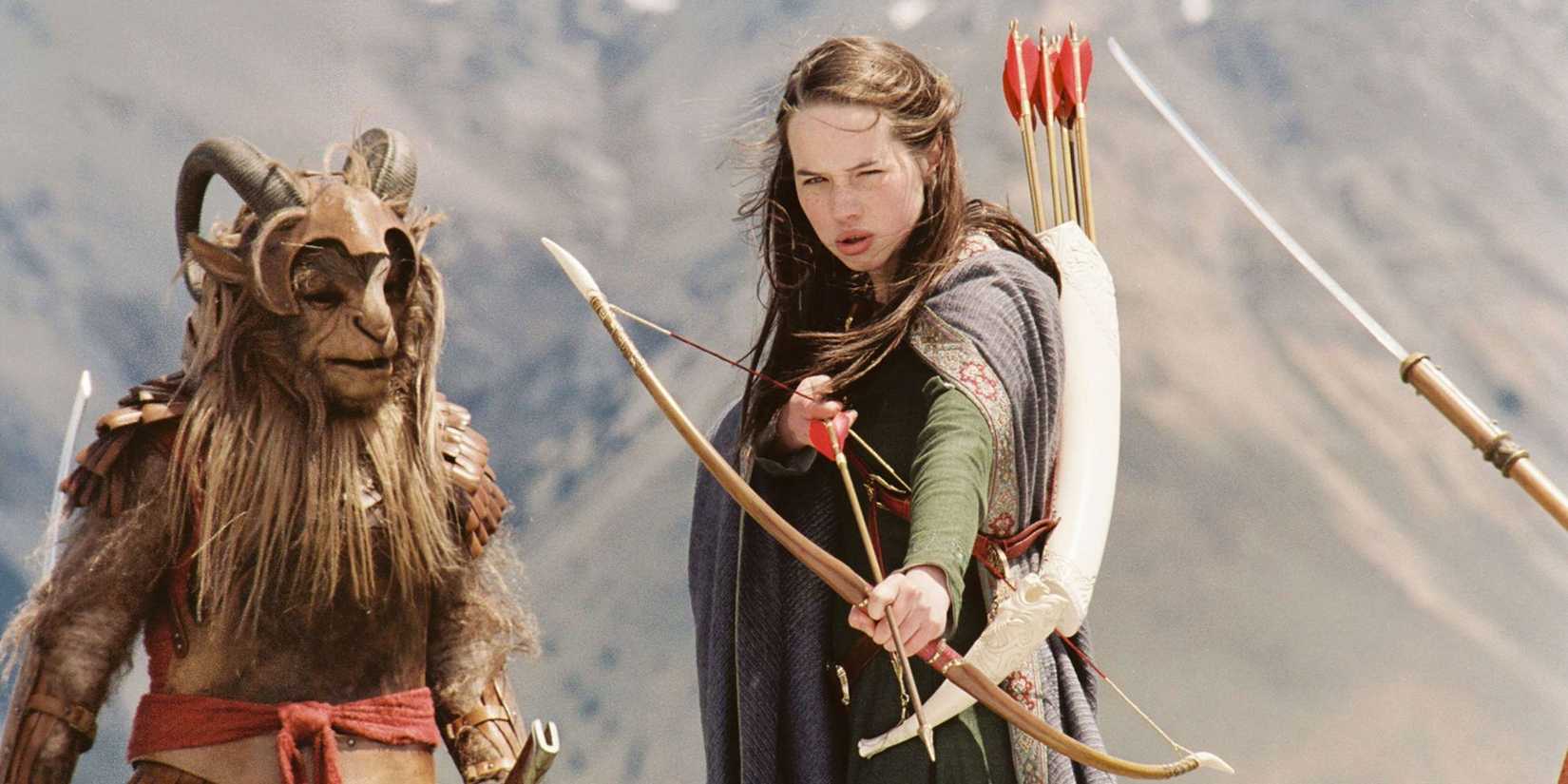 Anna Popplewell as Susan drawing a bow and arrow with a fantasy creature nearby in The Chronicles of Narnia: The Lion, the Witch and the Wardrobe.
