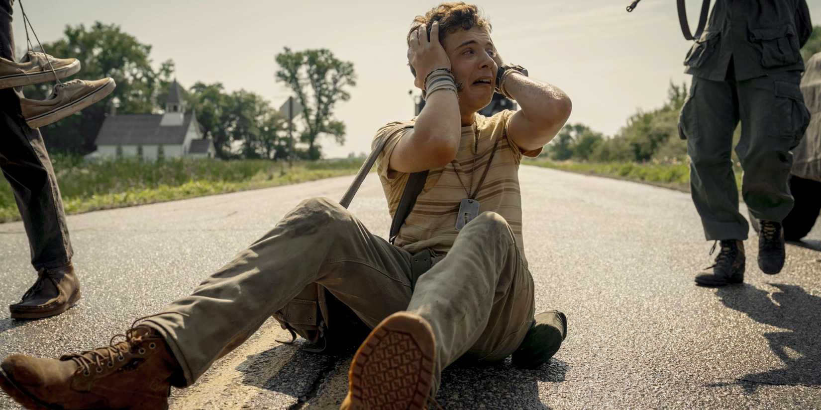 The Long Walk - a traumatized competitor sits on the ground with his hands on his head