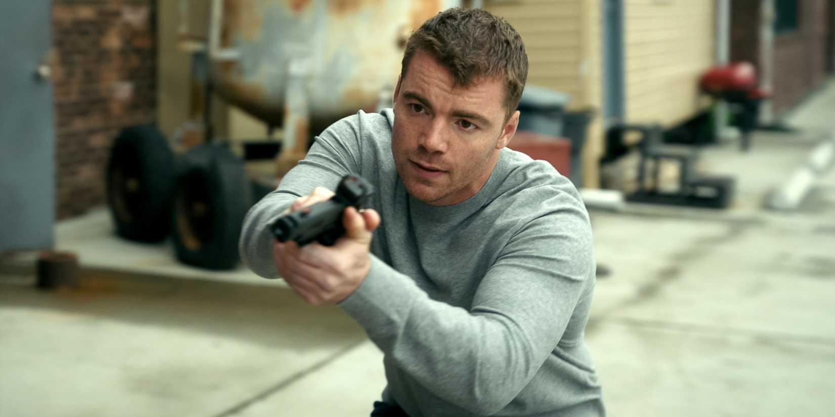 Gabriel Basso as Peter Sutherland holding out his gun with both hands in The Night Agent Season 3