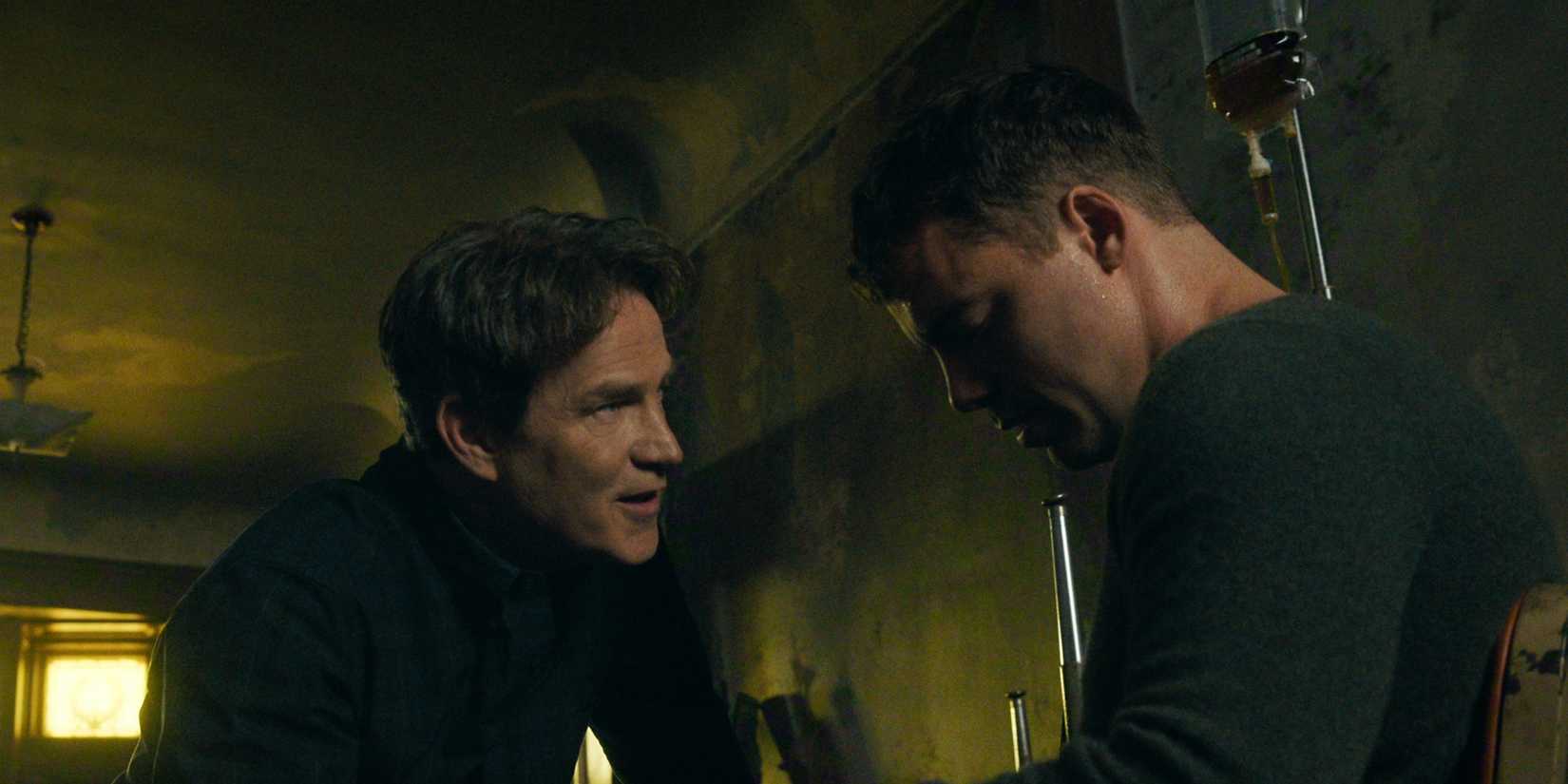 Stephen Moyer as the assassin kneeling next to a sitting Gabriel Basso as Peter in The Night Agent Season 3