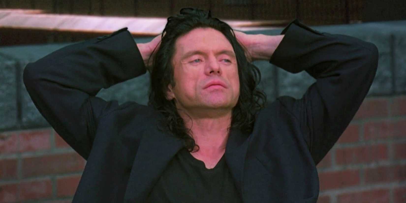 Tommy Wiseau leaning back on a chair in The Room