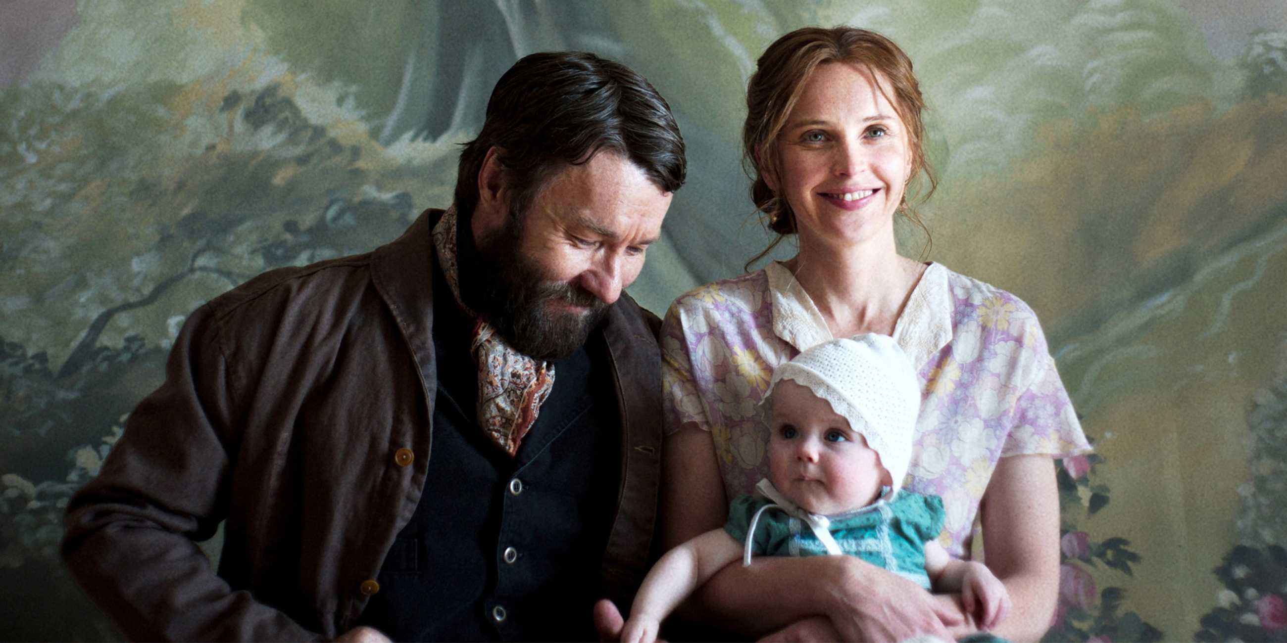 Joel Edgerton's Robert smiling and posing with Felicity Jones' Gladys and their baby in Train Dreams