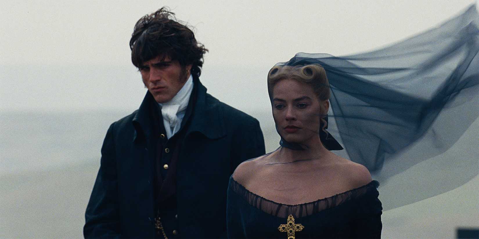 Margot Robbie as Catherine and Jacob Elordi as Heathcliff standing together at a funeral in Wuthering Heights