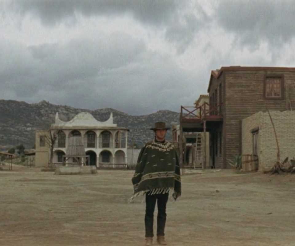 The Man with No Name approaching two other men in A Fistful of Dollars