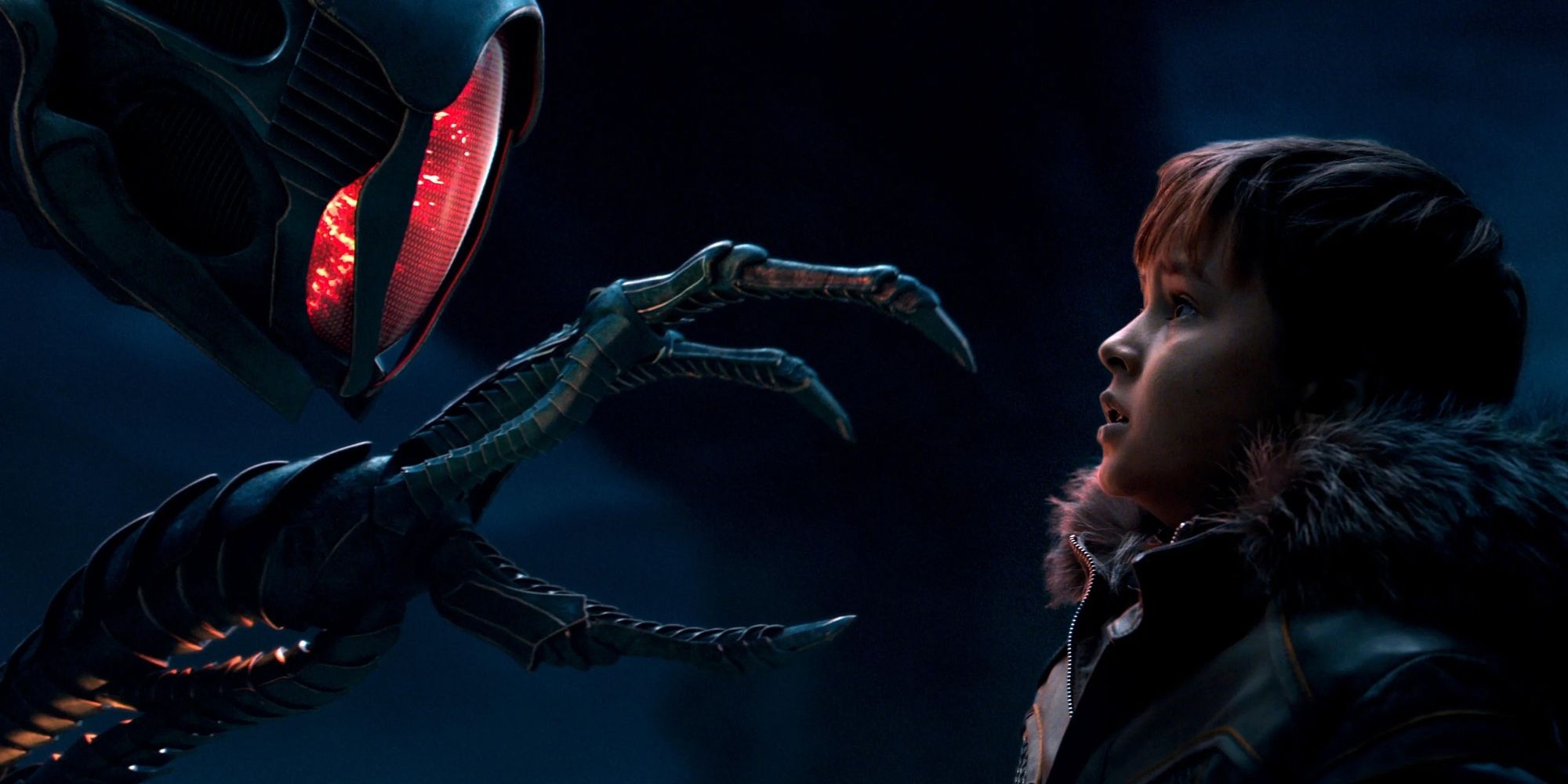 An alien robot reaches its hand out to Will Robinson (Maxwell Jenkins) in Lost in Space.