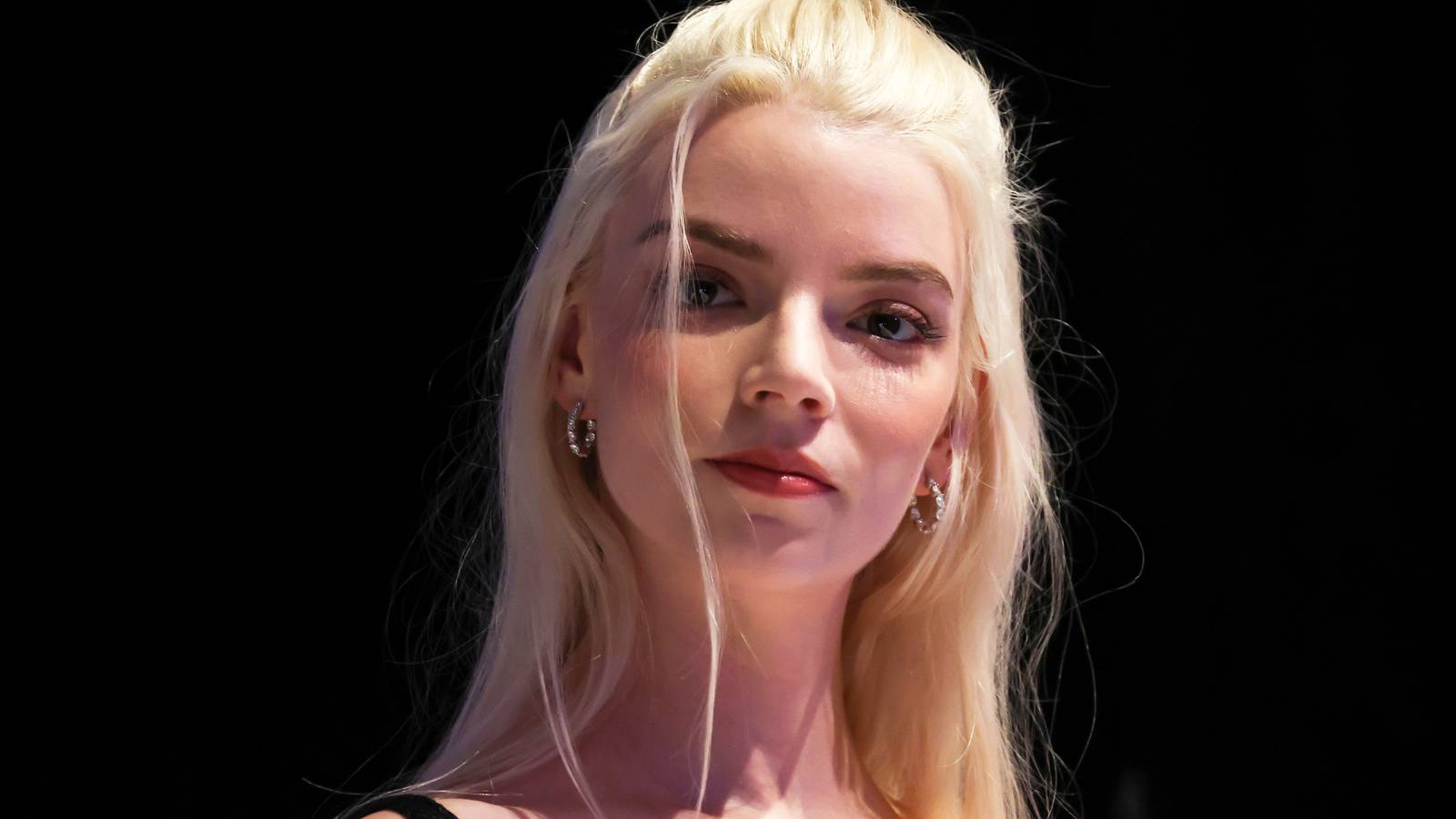 Anya Taylor-Joy smiling in front of a black background