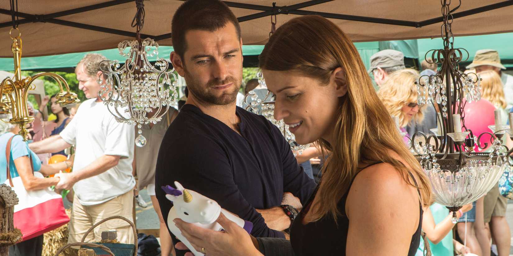 Ivana Milicevic and Antony Starr looking at a toy unicorn in Banshee