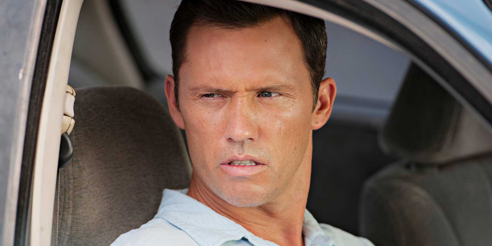 Jeffrey Donovan olhando estoicamente pela janela do carro em Burn Notice