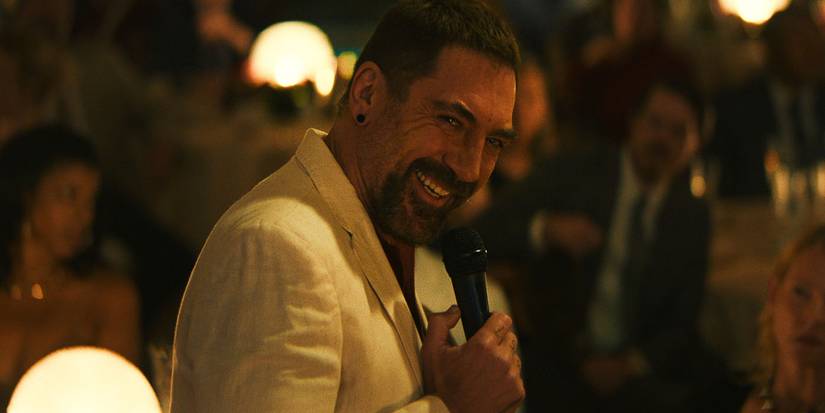 A man in a white suit smiling creepily while holding a mic in Cape Fear.