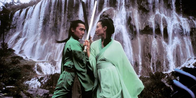 A man and a woman have a swordfight against a waterfall