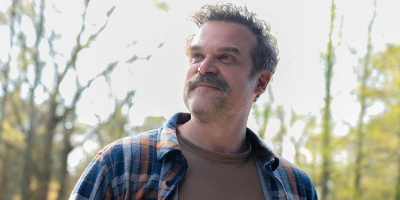 David Harbour as Floyd looking off to the right with a slight smile while standing outside in DTF St. Louis
