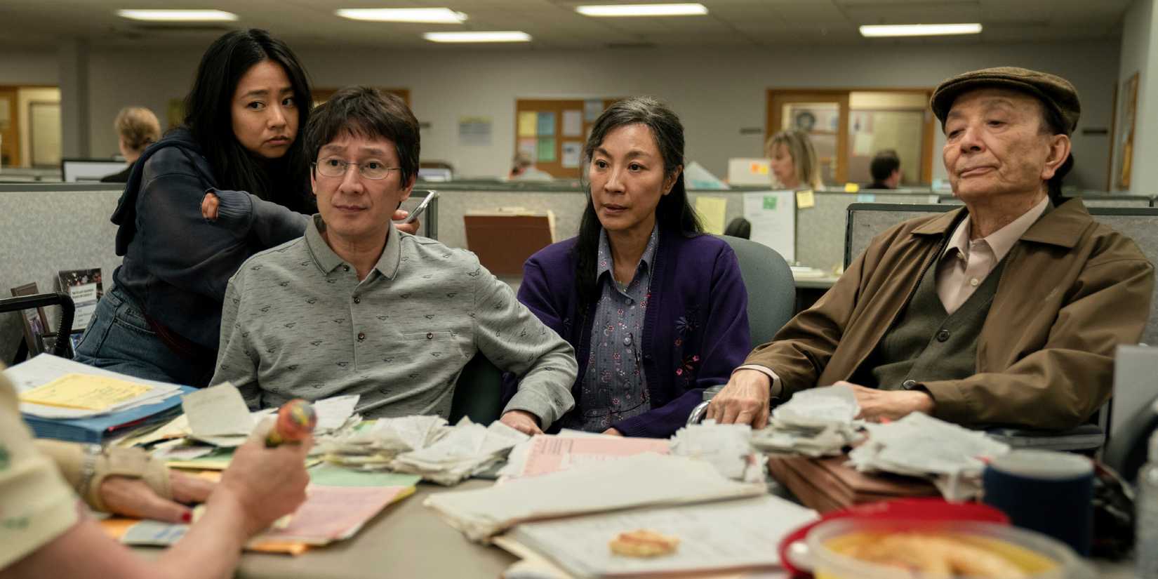 The cast of Everything Everywhere All at Once sitting behind a desk