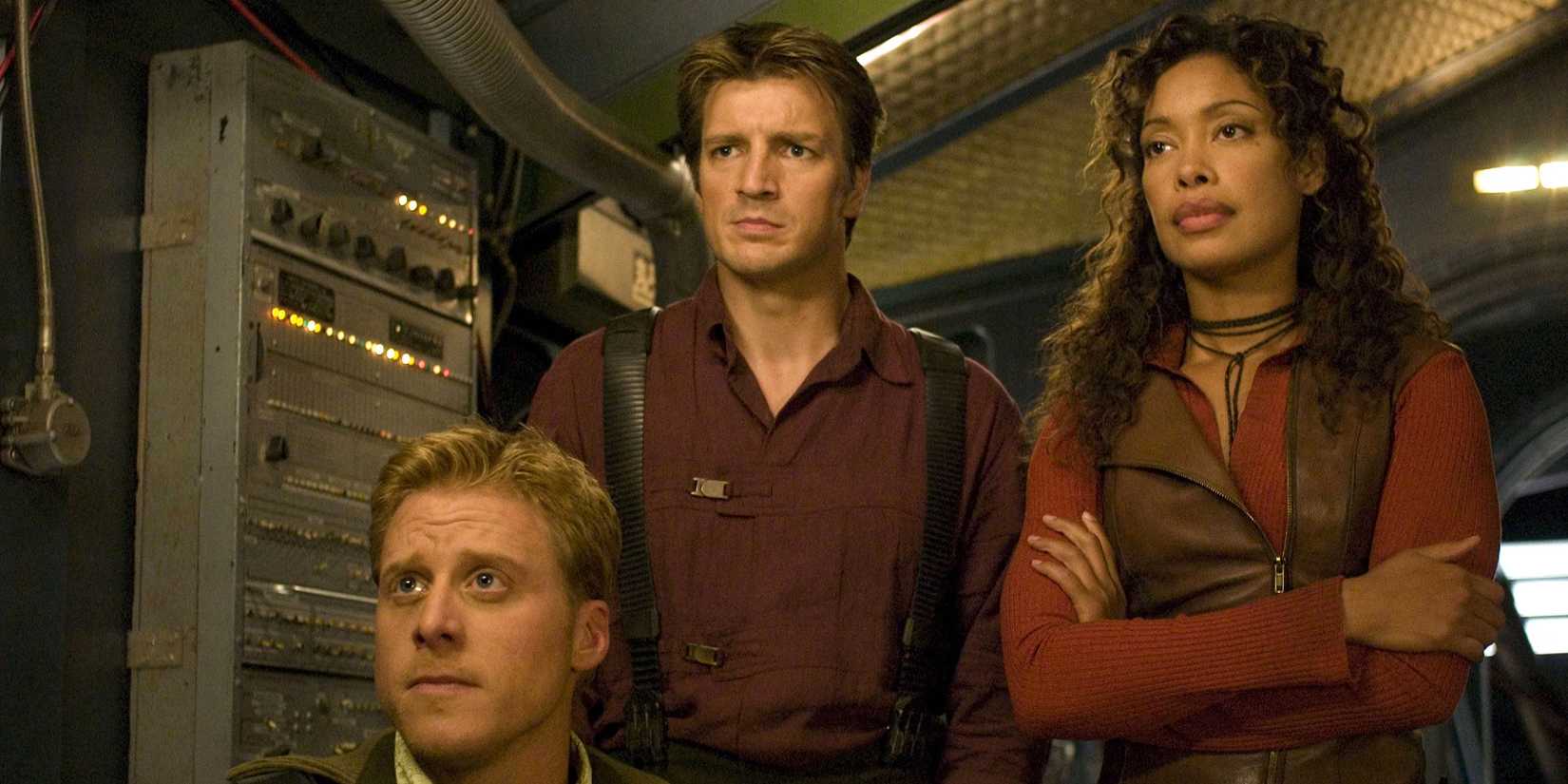 Alan Tudyk, Nathan Fillion, and Gina Torres staring at something in the ship in Serenity