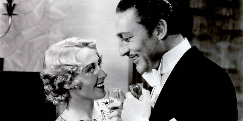 Carol (Joan Blondell) and J. Lawrence Bradford (Warren William) looking at each other and smiling.