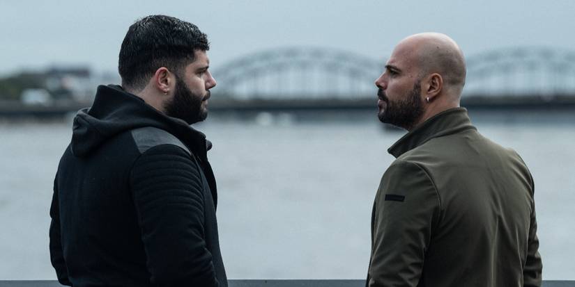 Salvatore Esposito and Marco D'Amore talking next to a body of water during a grim day in Gomorrah