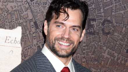 Henry Cavill smiles off to the side in a red carpet photo