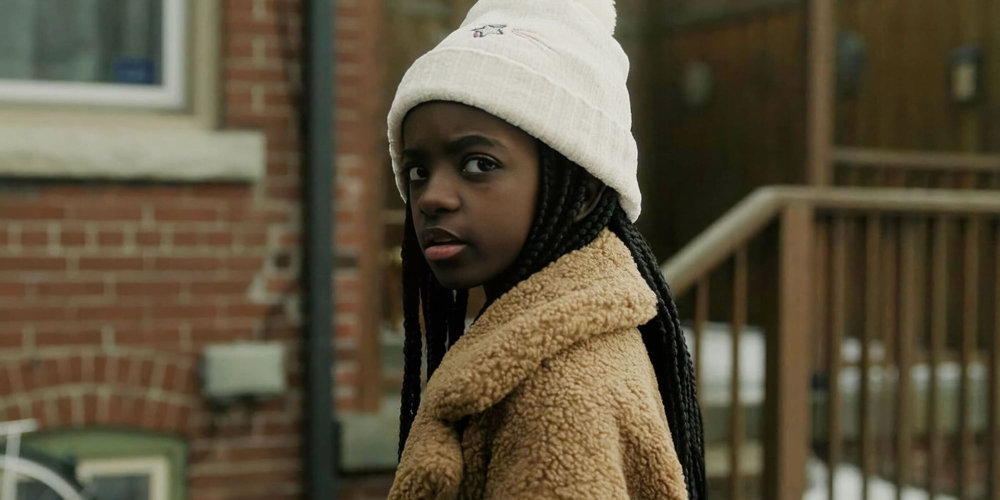 A little girl wearing a beanie looking at something in Cross