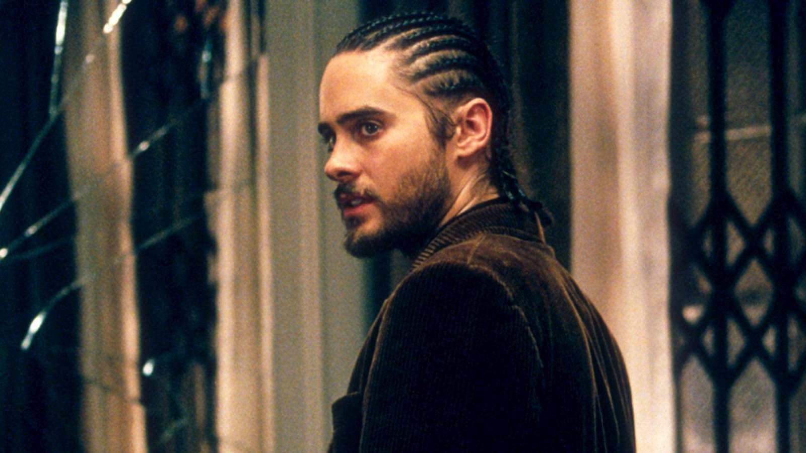 Jared Leto with his hair in cornrows looks over his shoulder at someone in Panic Room