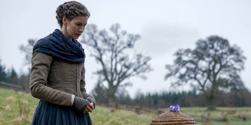 Caitriona Balfe as Claire looking at a bee hive at the Ridge in Outlander Season 8