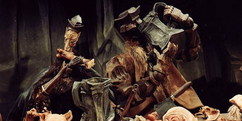 The piper sits at a table playing his pipe.