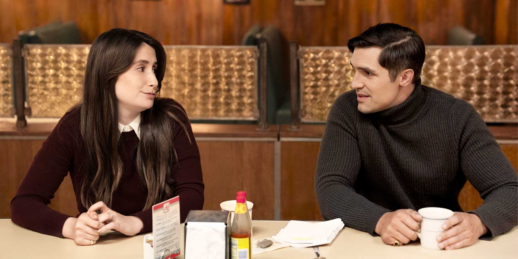Katie and Archie sit at a restaurant talking.
