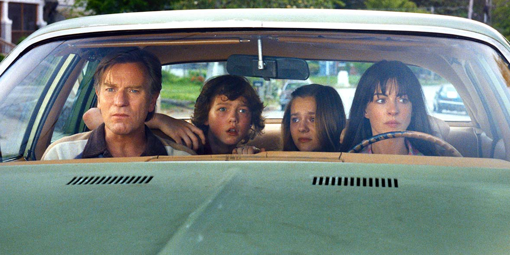 Ewan Mcgregor and Anne Hathaway sit in a car with their children in 'The End of Oak Street'
