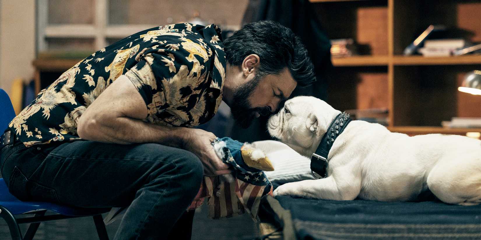 Billy Butcher leans over and touches noses with a dog.