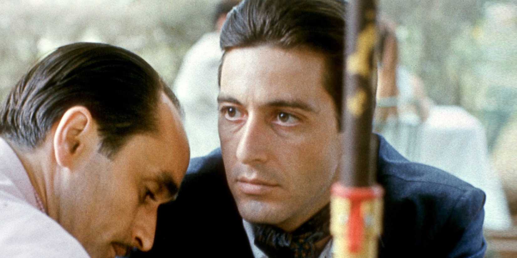 Al Pacino as Michael Corleone looking into the distance with a blank expression next to John Cazale as Fredo Corleone in The Godfather Part II (1974)