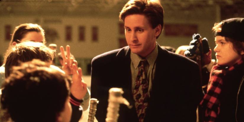 Emilio Estevez, Joshua Jackson, and the other cast huddle on the ice in The Mighty Ducks