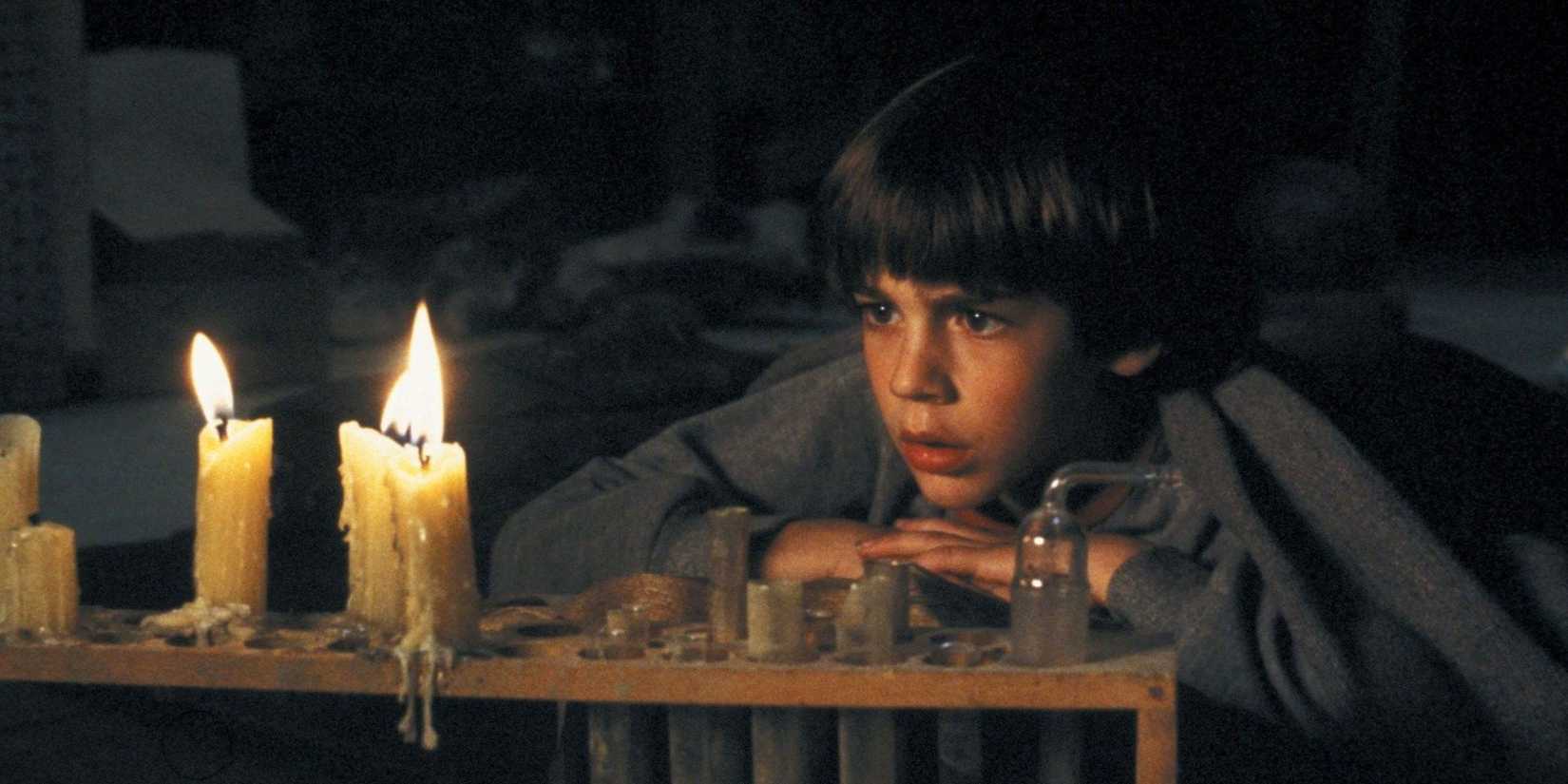 Barret Oliver as Bastian reading a book by candlelight and looking compelled in The NeverEnding Story