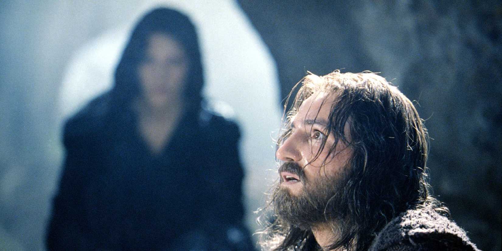 Rosalinda Celentano out of focus in the background as Jim Caviezel looks up anxiously in The Passion of the Christ
