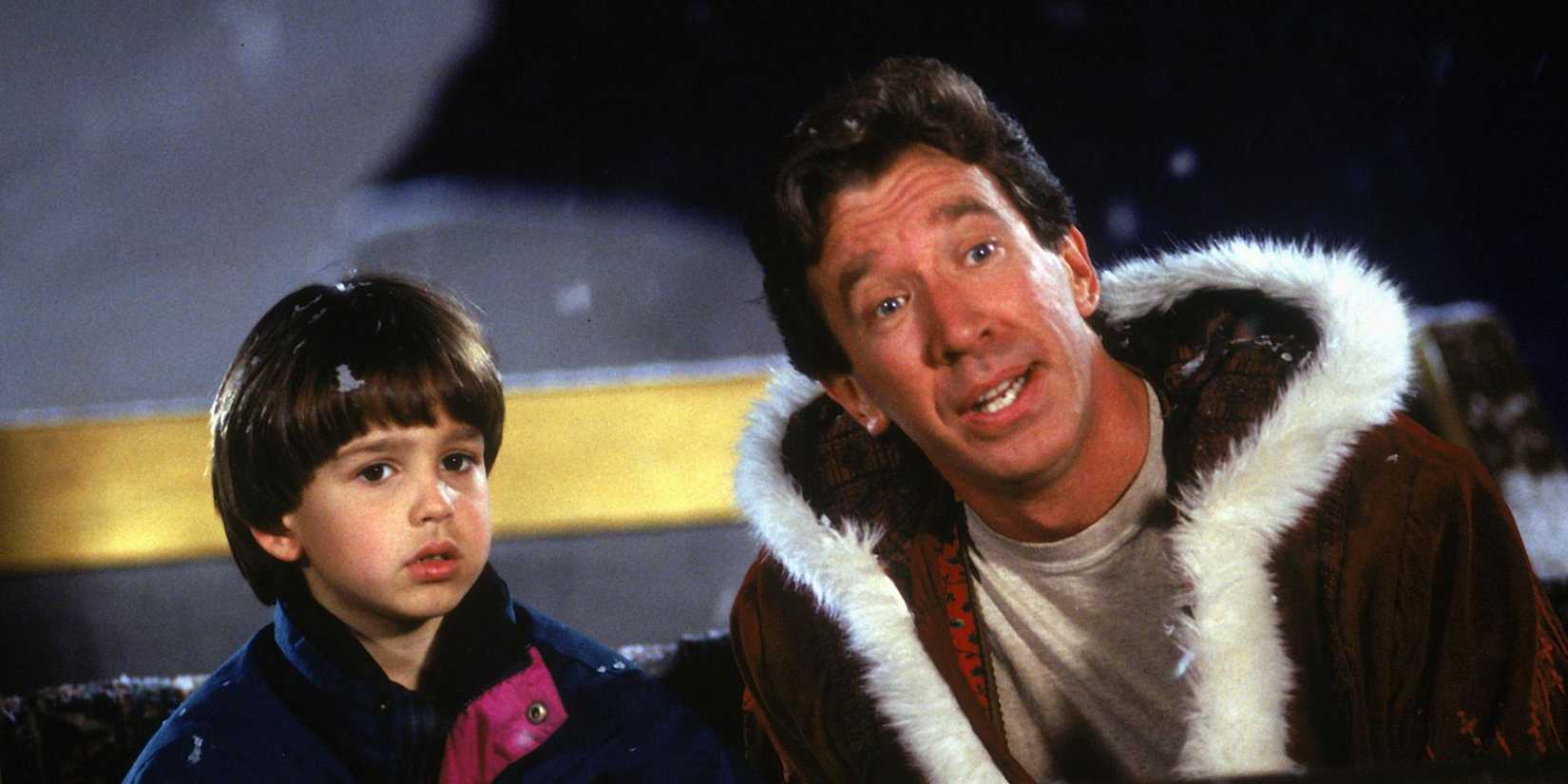 Tim Allen as Scott and Eric Lloyd as Charlie sit in Santa's sleigh together and look ahead in The Santa Clause