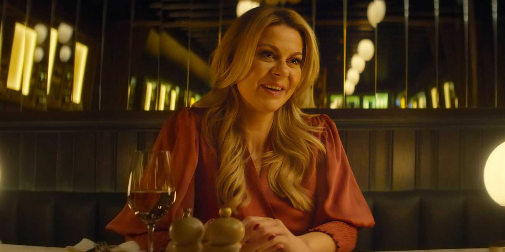 A woman has wine at a fancy restaurant in Tinder Swindler