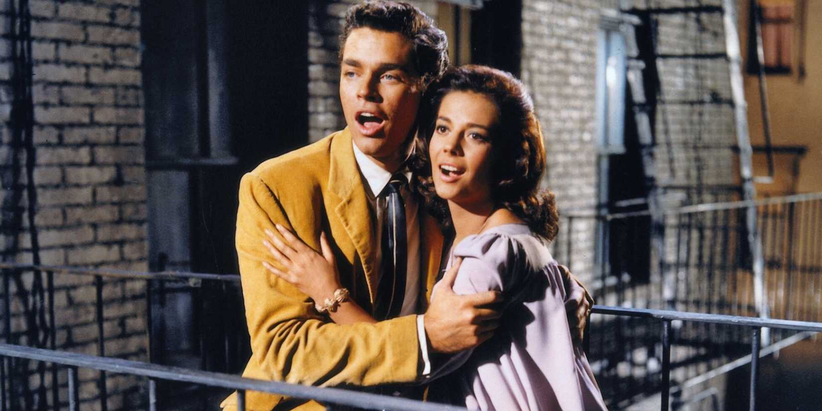 Richard Beymer as Tony and Natalie Wood as Maria embracing and singing while standing on a balcony in West Side Story (1961)