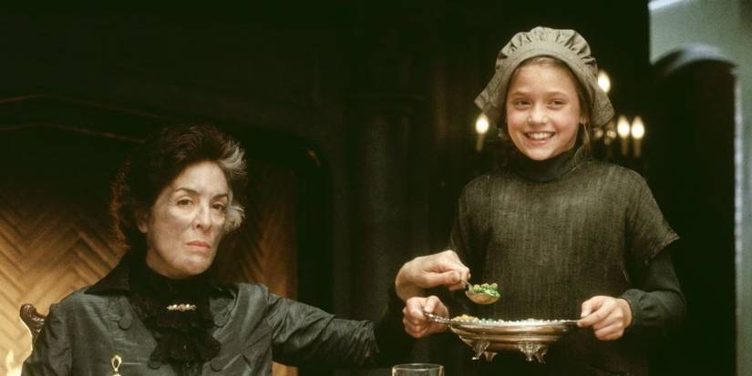 Liesel Matthews as Sara dressed in rags stands next to Eleanor Bron as Miss Minchon in A Little Princess